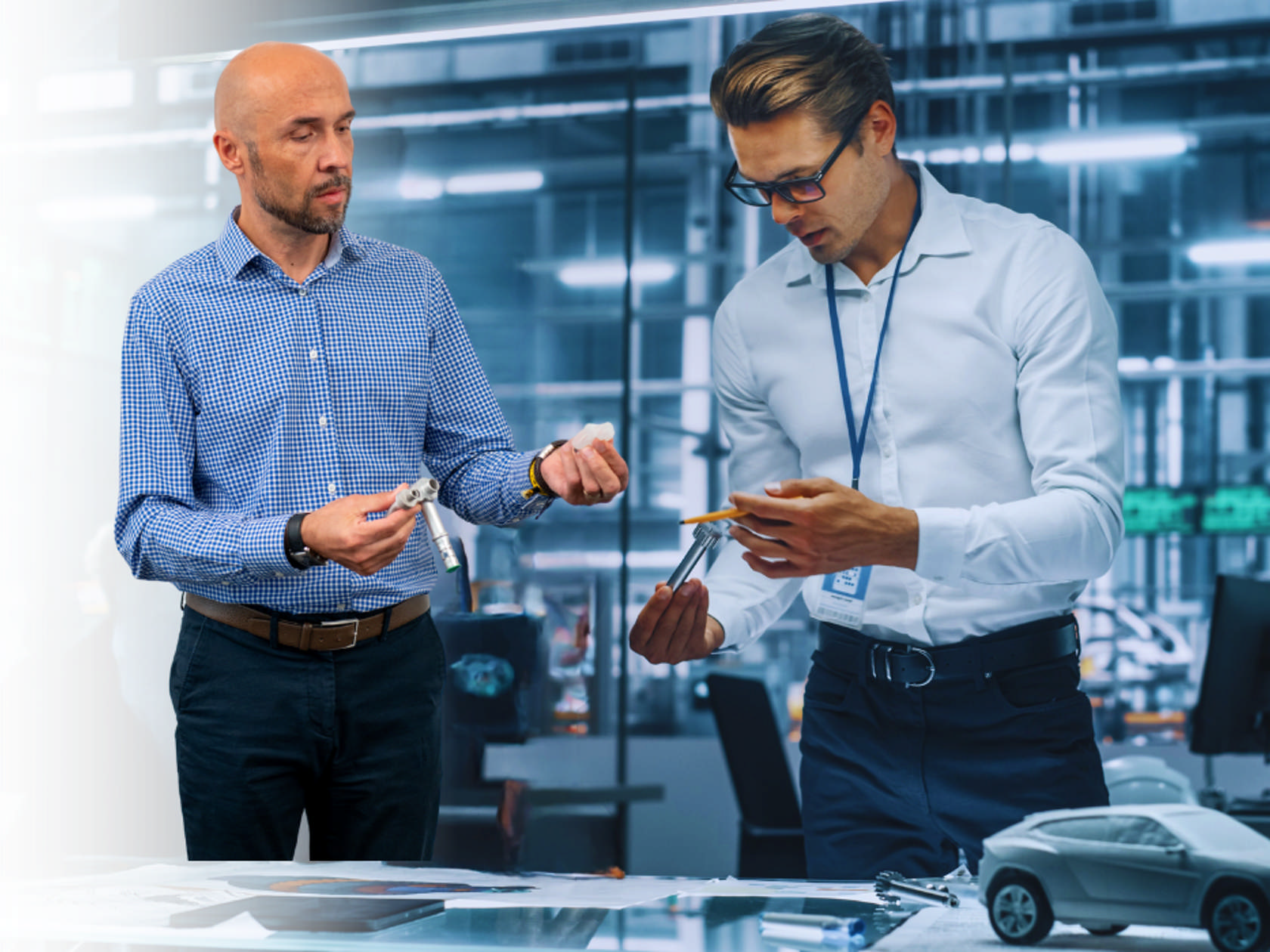 Two engineers discussing DBI parts and design in a modern office with a car model.